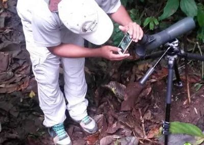 Ein Mann vor einem Spektiv mit Blättern auf dem Boden