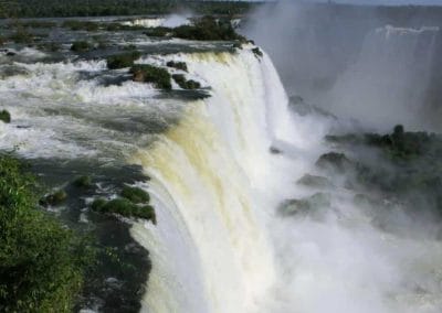 A large waterfall coming out of the water with Iguazu Falls in the background