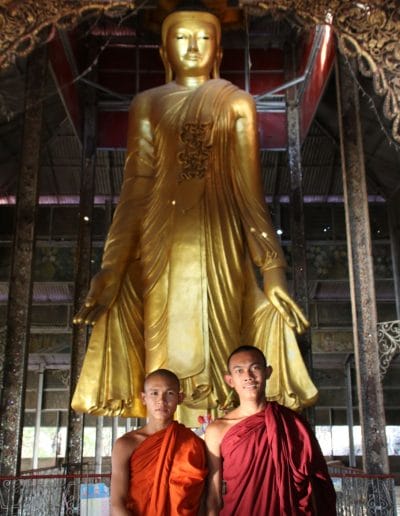 Stehender goldener Buddha und 2 Mönche in roten Kutten