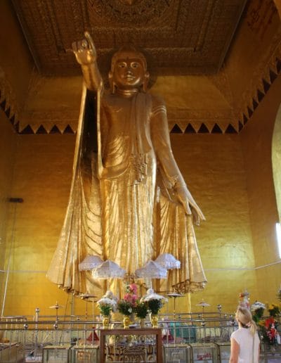 Stehender goldener Buddha und Blumen