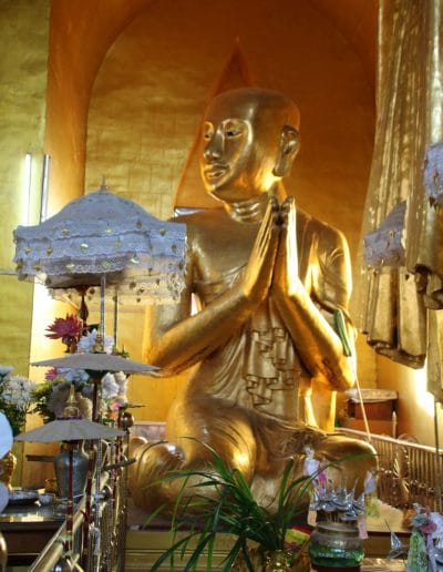 Sitzender goldener Buddha und Blumen