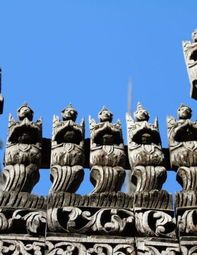 Figuren aus Holz geschnitzt vor blauem Himmel