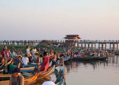 Menschen in Booten vor Holzbrücke