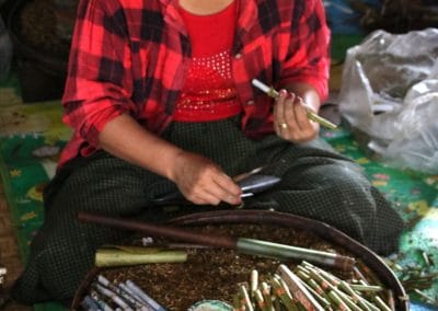 Frau mit roten Hemd vor Tisch der mit Zigarillos bedeckt ist