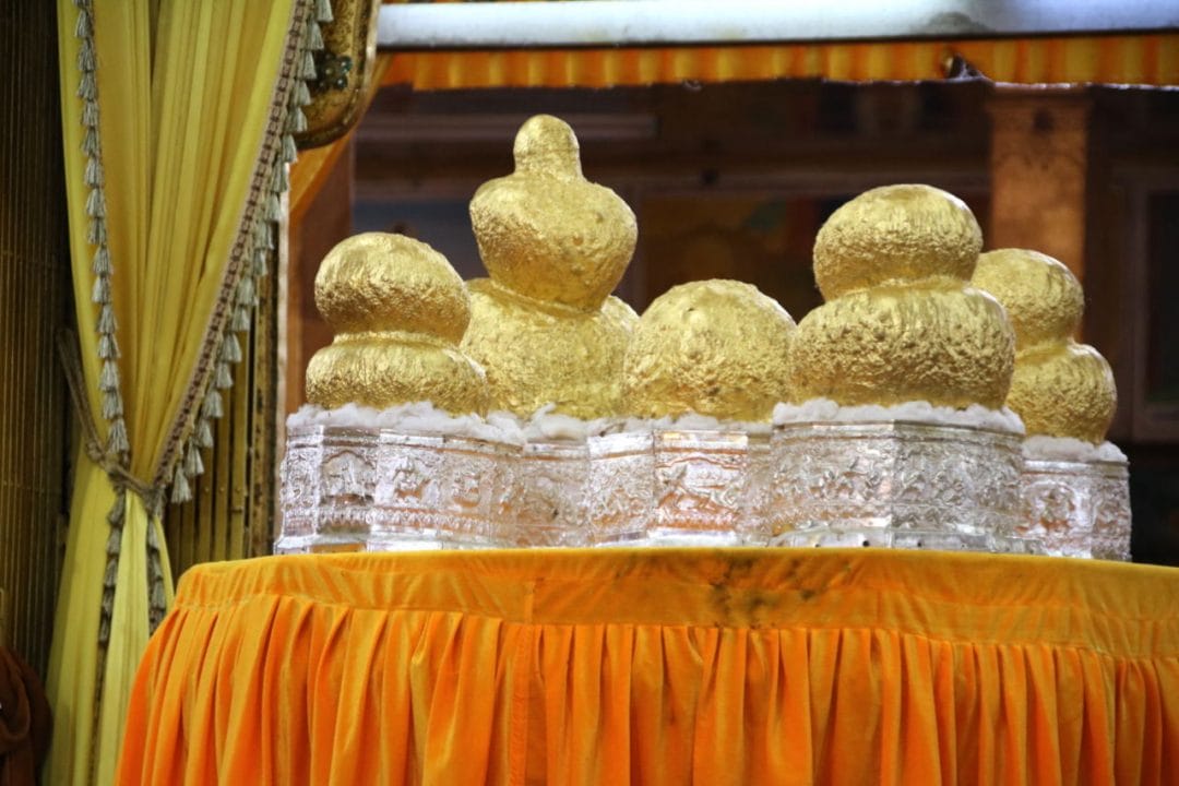Buddha Figuren aus Gold auf einem Tisch mit oranger Decke