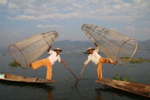 Zwei Männer mit Netzkörben in zwei Booten auf einem See