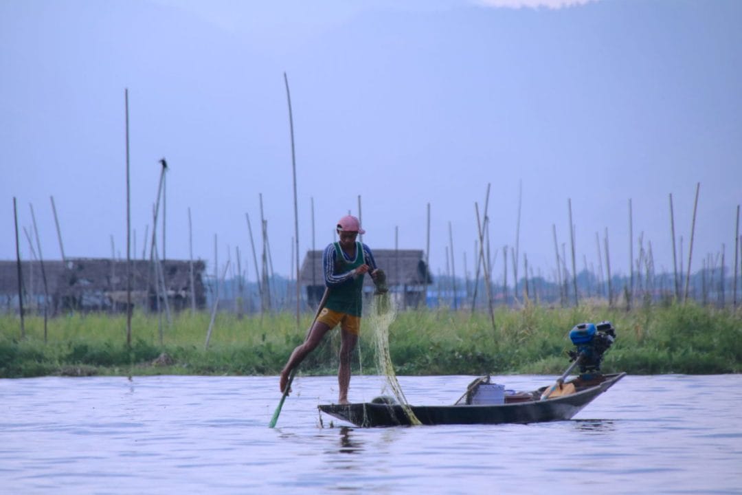 Ein Fischer mit einem Netz auf einem Boot auf dem Inlesee