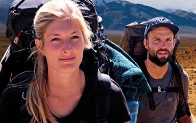 Ein Mann und eine Frau mit Rucksäcken in der Wüste.