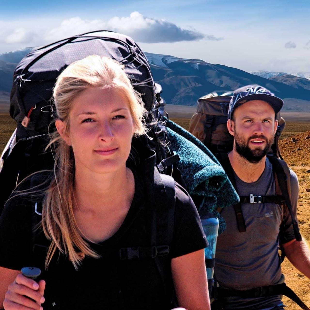 Ein Mann und eine Frau mit Rucksäcken in der Wüste.