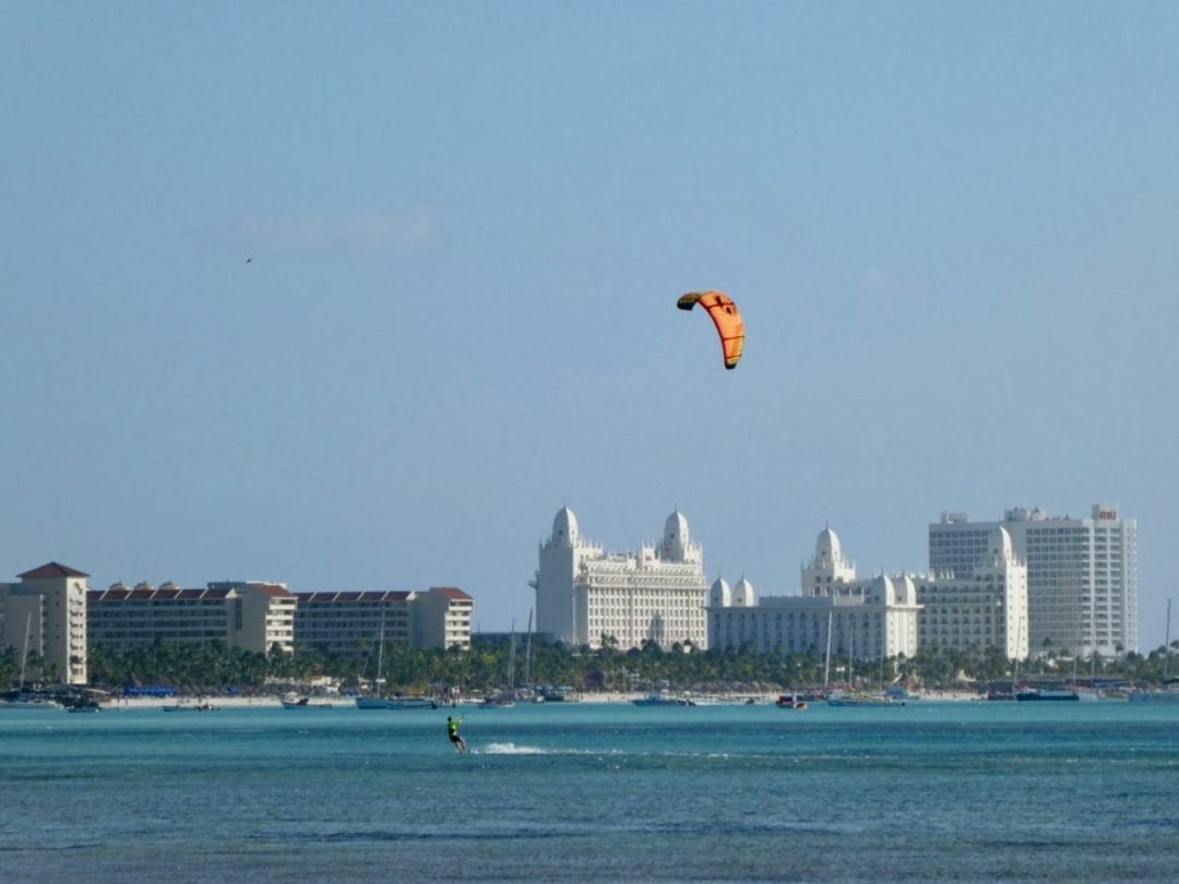 Ein Kitesurfer im Meer mit blauem Himmel und Hotels im Hintergrund