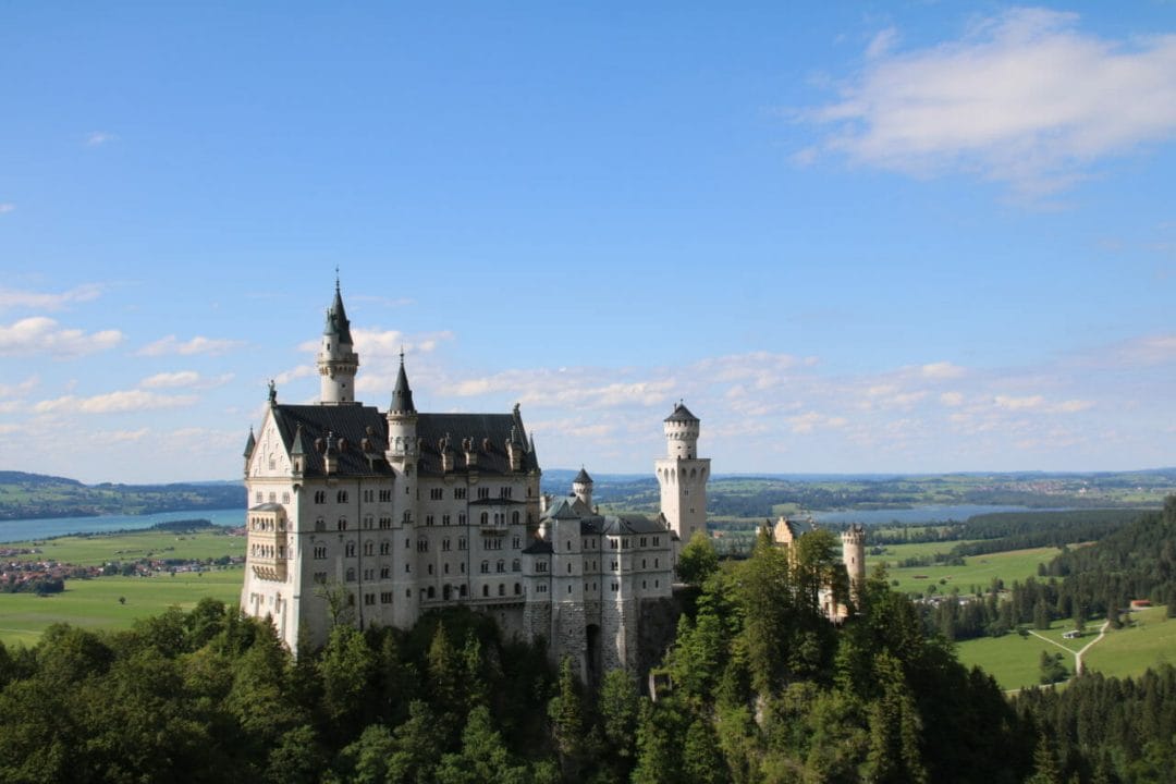Das Schloss Neuschwanstein mit Seen und Wiesn im Hintergrund