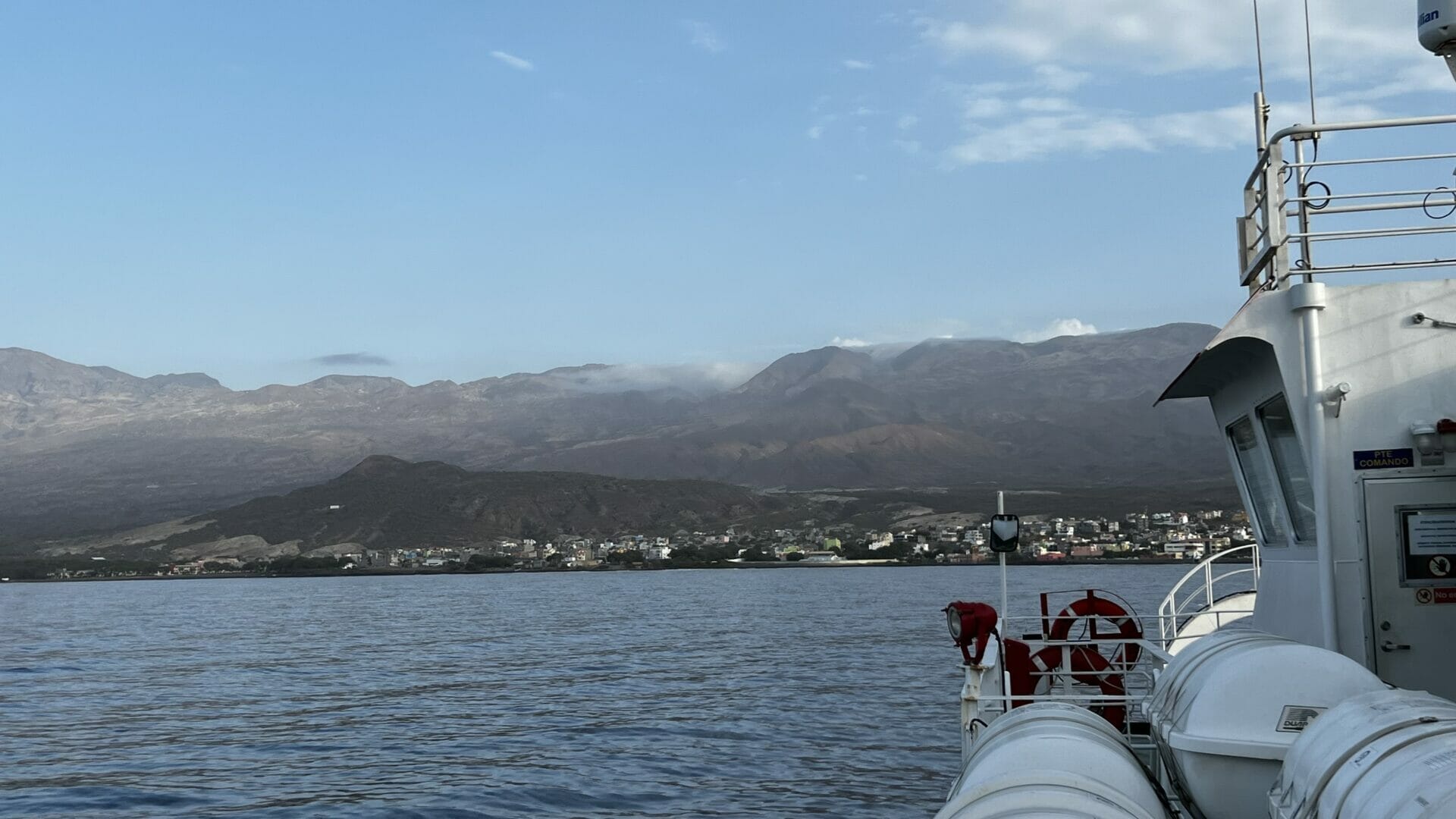 Eine Fähre im Wasser mit Bergen im Hintergrund.