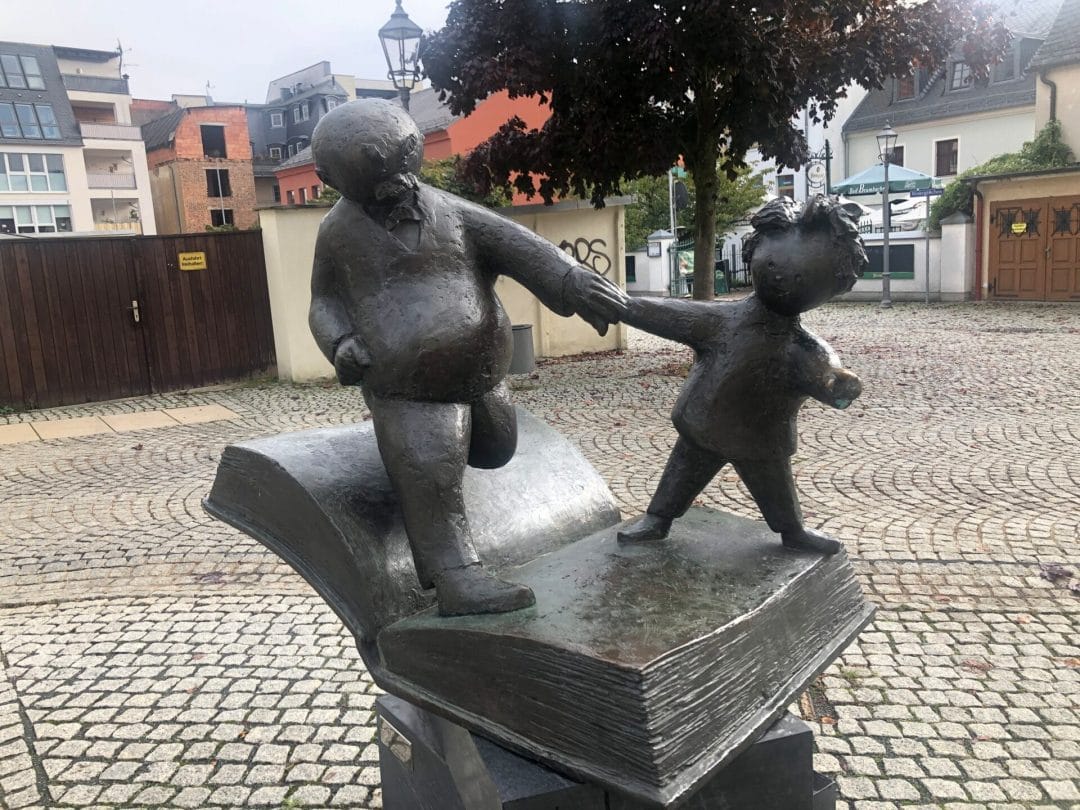 Eine Statue eines Jungen und eines Mädchens, die ein Buch an den Händen halten.